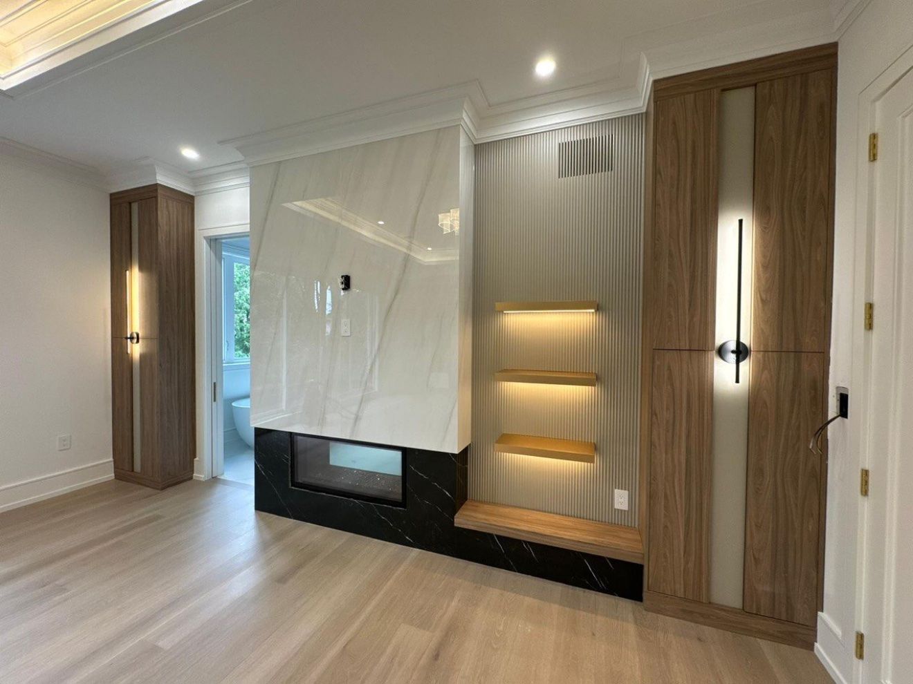 Bedroom fireplace wall with marble, fluted panels and lit shelves