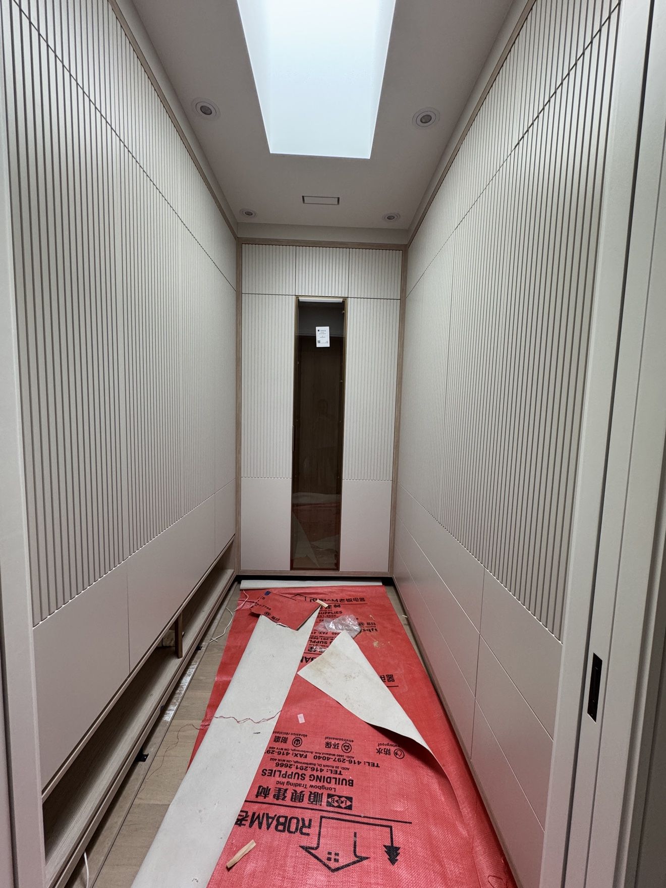Fluted-panel dressing room corridor with skylight, during finishing