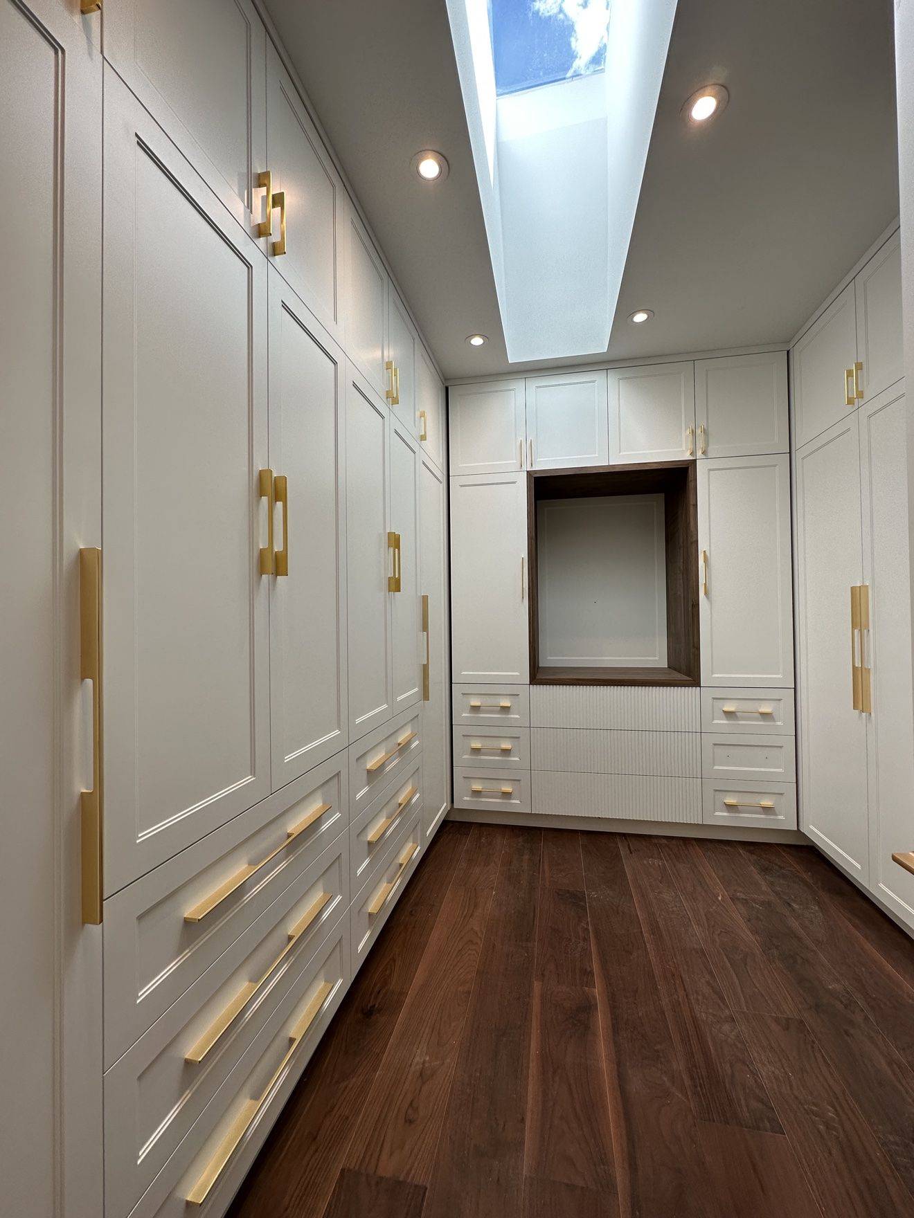 Walk-in closet corridor with floor-to-ceiling wardrobes and drawers