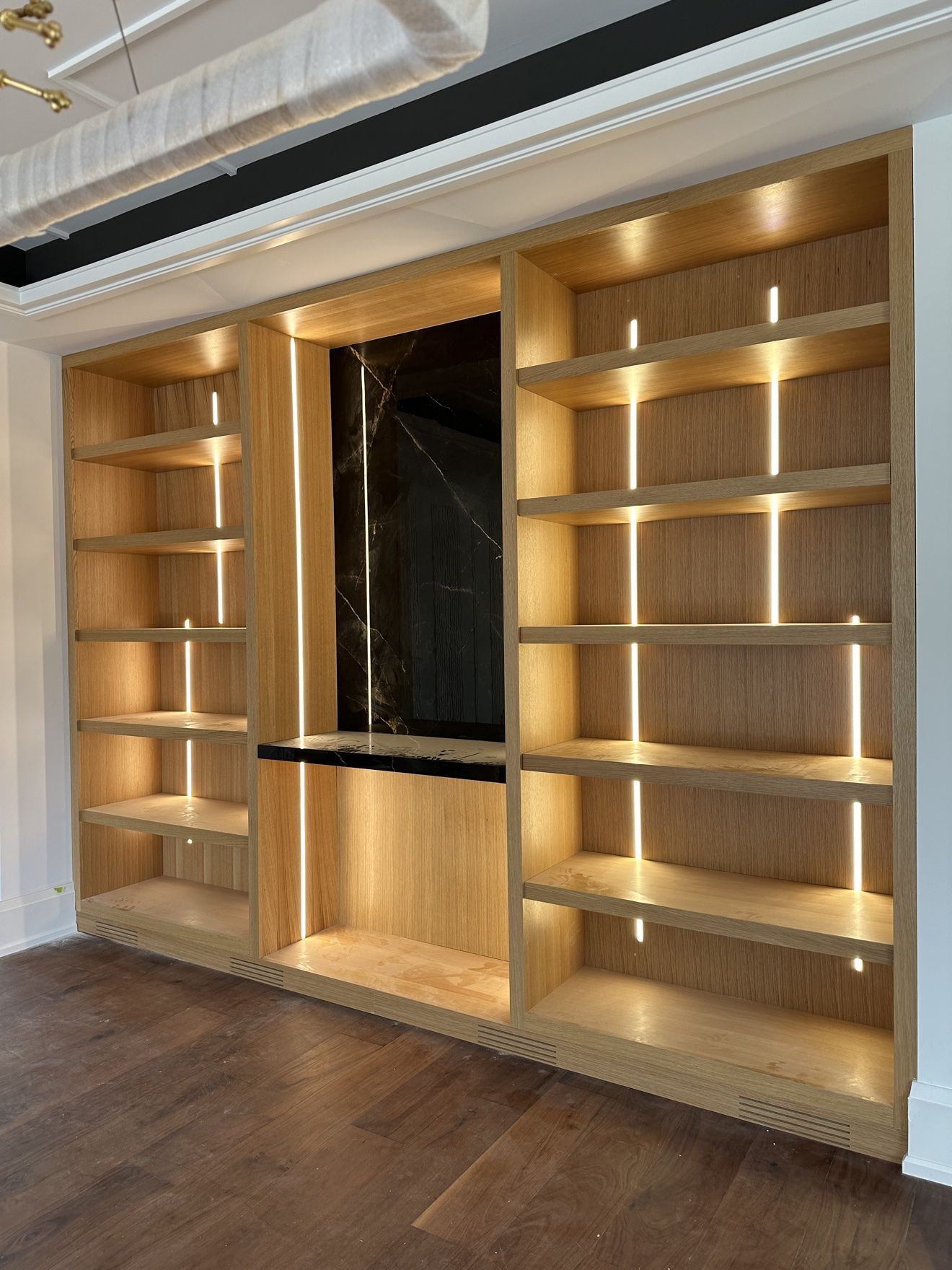 Light oak display wall with vertical LED light strips and black marble centre panel