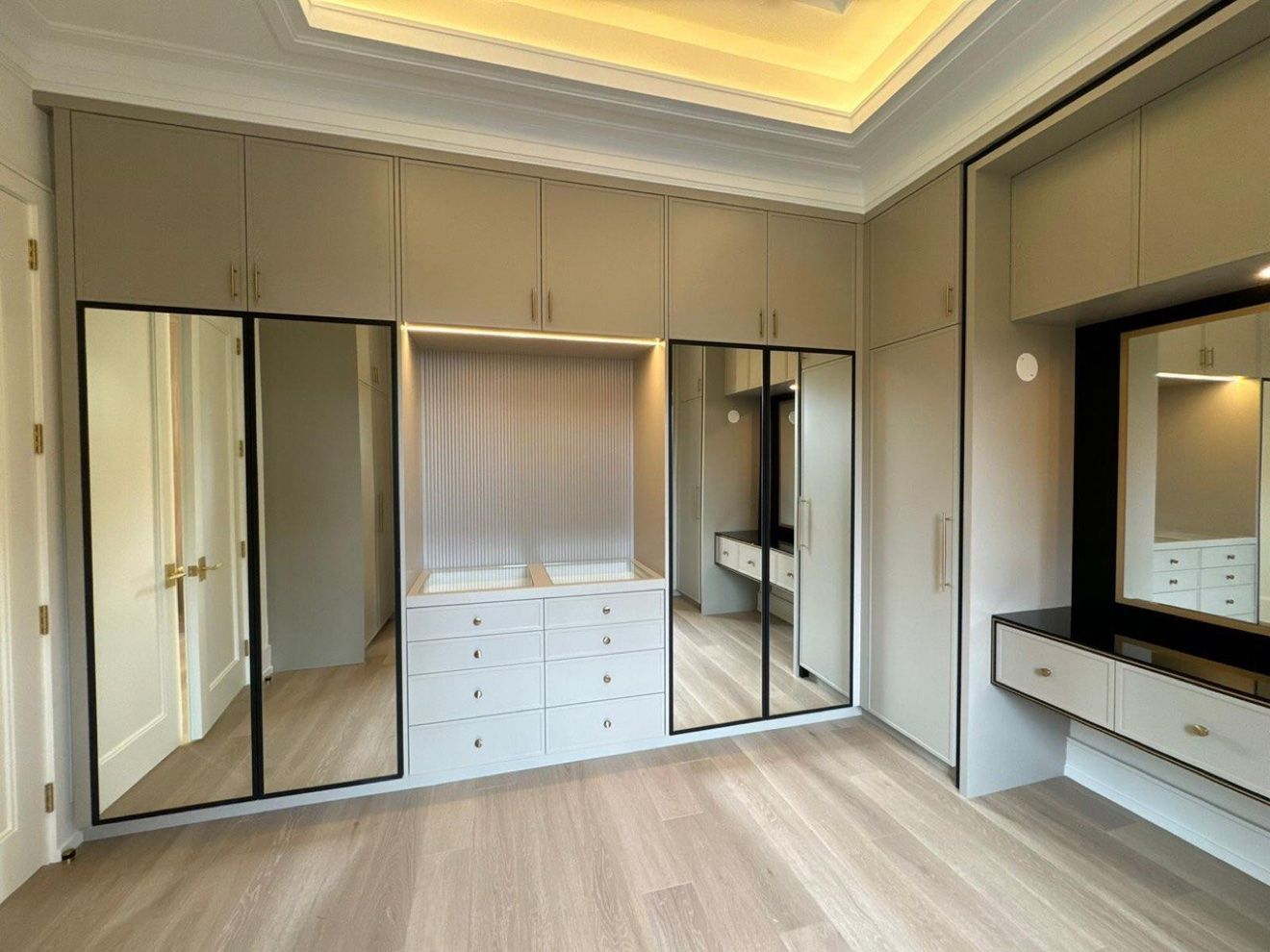Dressing room with mirrored wardrobes, glass-top drawers and vanity