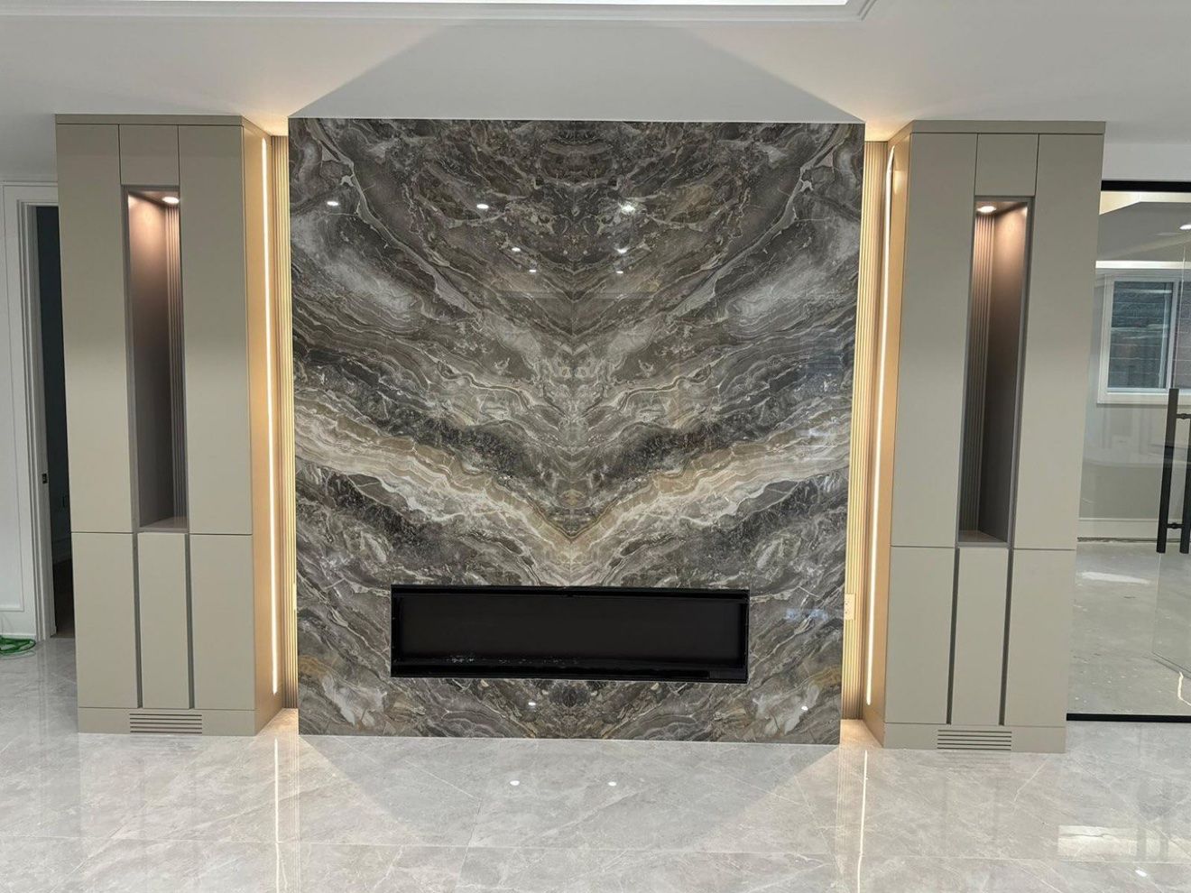 Book-matched stone fireplace wall with LED channels and lit niches