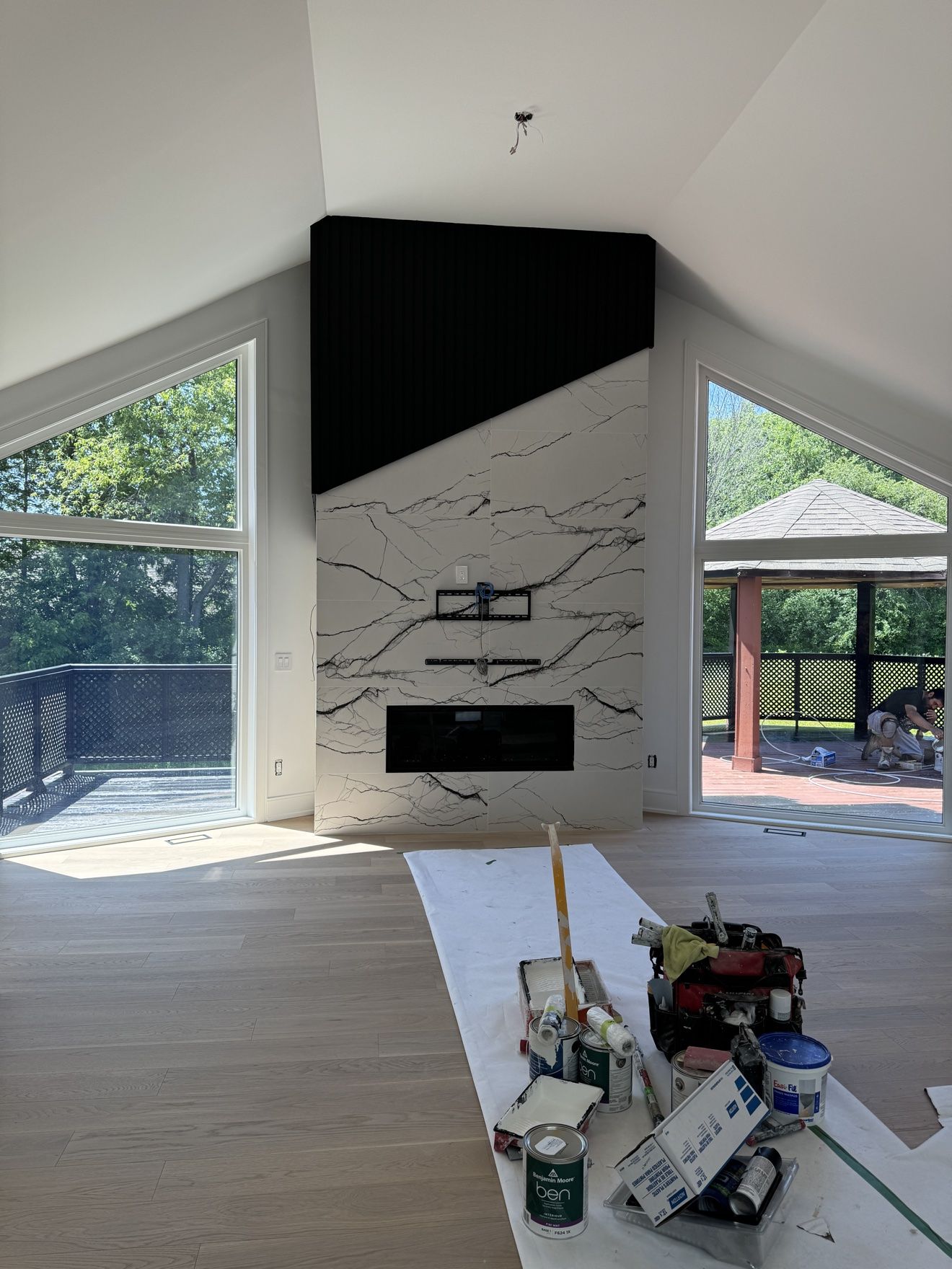 Vaulted living room fireplace wall in veined stone with black fluted panel