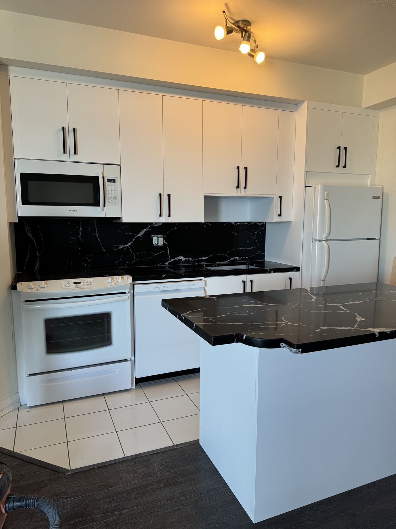 White condo kitchen with black marble counters, backsplash and island