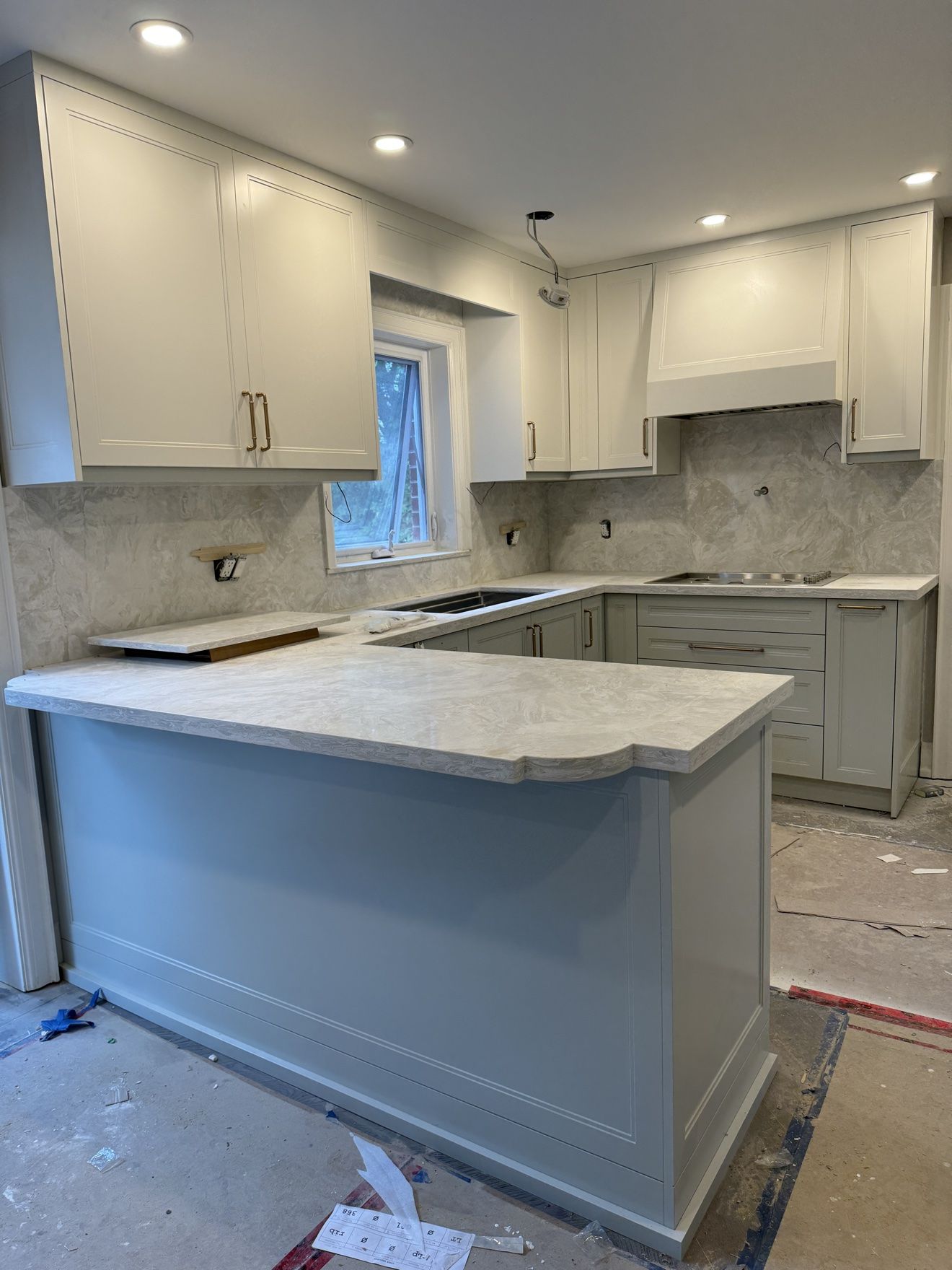 Two-tone shaker kitchen in cream and sage with marble-look stone and brass hardware