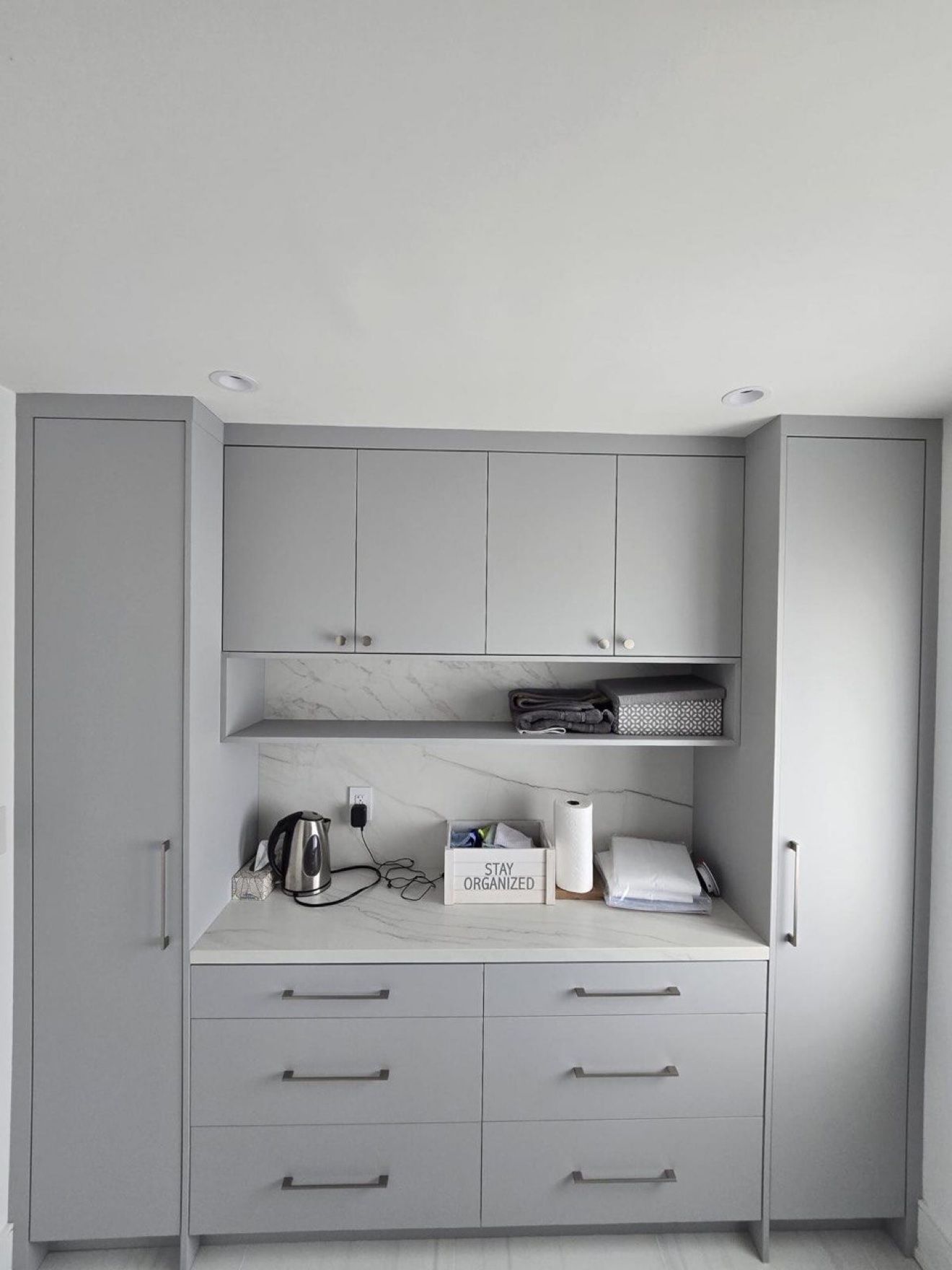 Grey laundry room cabinetry with marble backsplash