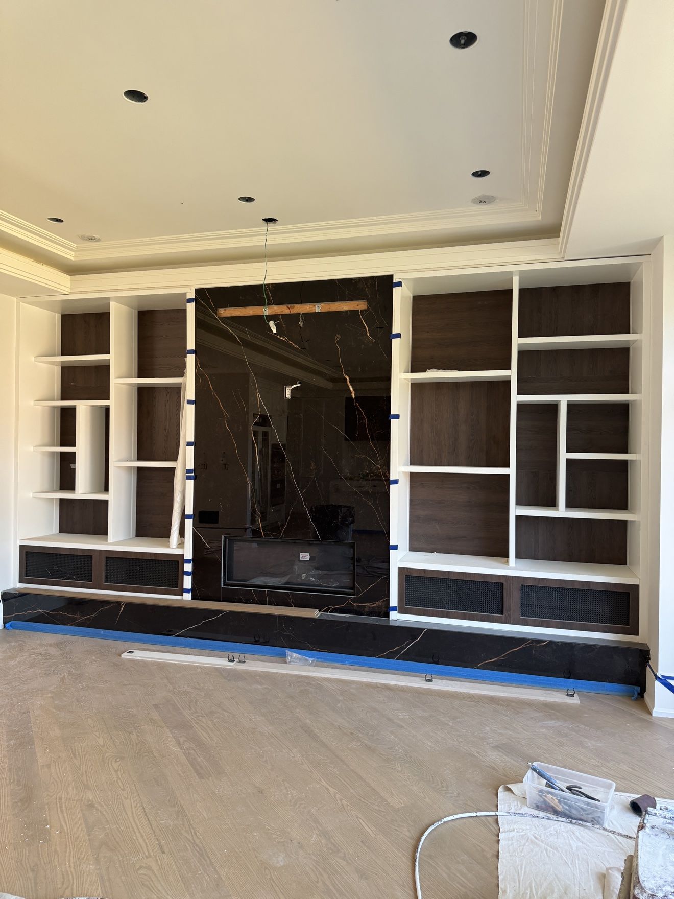 Media wall with black marble centre, built-in shelving and linear fireplace
