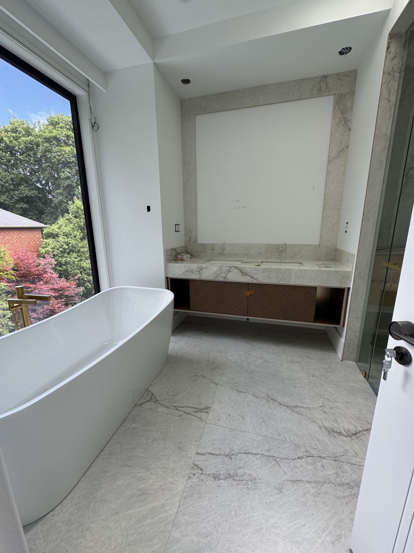 Primary bathroom with fluted walnut double vanity and freestanding tub