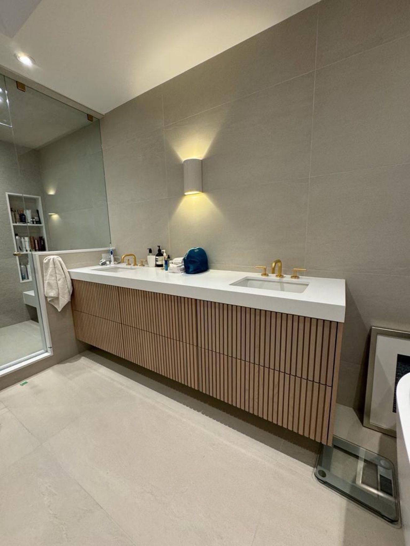 Fluted oak double vanity with brass faucets and wall sconce