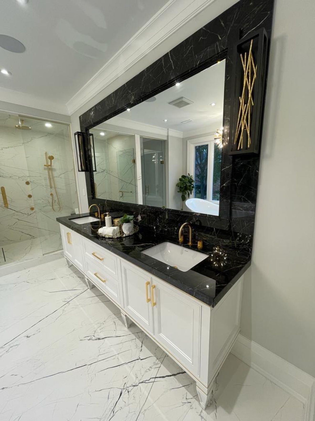 White double vanity with black marble counter and brass faucets