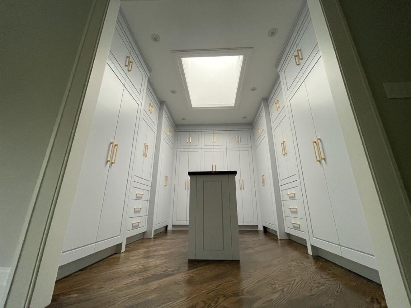 White walk-in closet with brass hardware and centre island